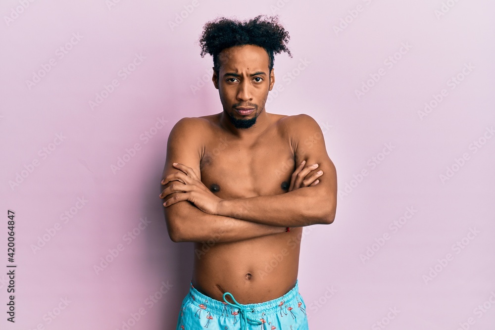 Fototapeta premium Young african american man with beard wearing swimsuit skeptic and nervous, disapproving expression on face with crossed arms. negative person.