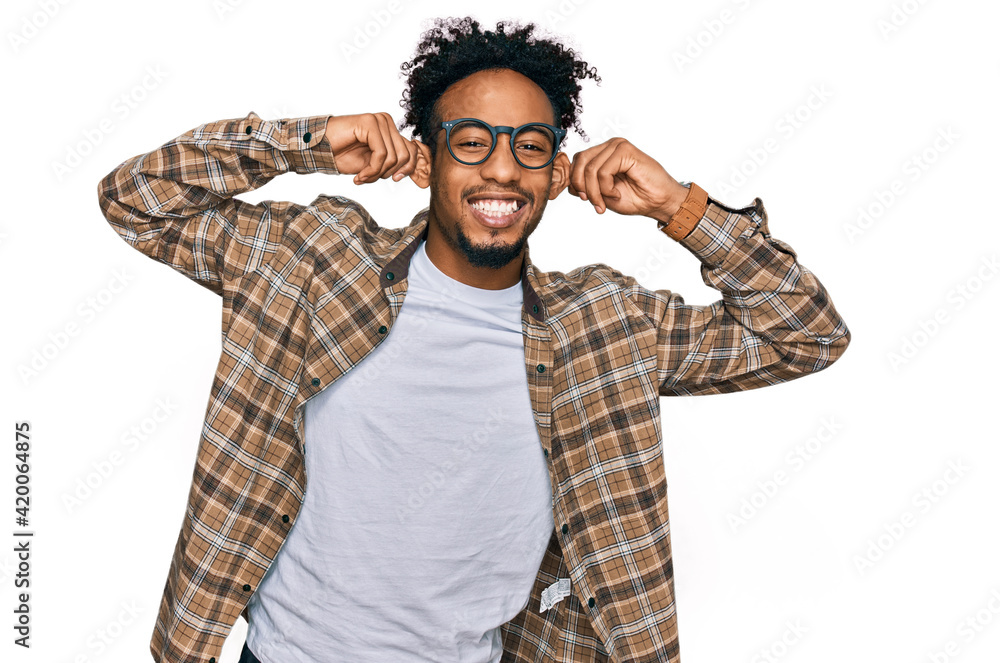 Young african american man with beard wearing casual clothes and glasses smiling pulling ears with fingers, funny gesture. audition problem Young african american man with beard wearing casual clothes and glasses smiling pulling ears with fingers, funny gesture. audition problem
