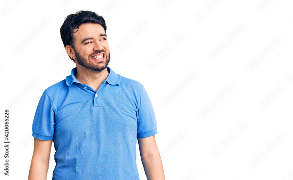 Young hispanic man wearing casual clothes looking away to side with smile on face, natural expression. laughing confident. Young hispanic man wearing casual clothes looking away to side with smile on face, natural expression. laughing confident.