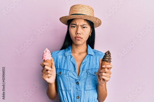 Young chinese woman wearing summer style holding ice cream clueless and confused expression. doubt concept.