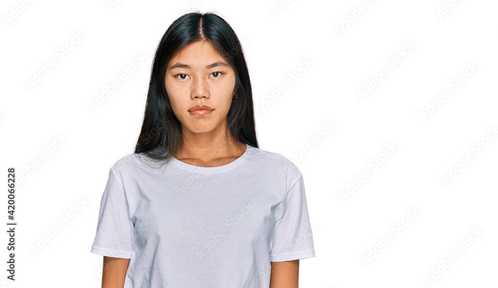 Beautiful young asian woman wearing casual white t shirt relaxed with serious expression on face. simple and natural looking at the camera. Beautiful young asian woman wearing casual white t shirt relaxed with serious expression on face. simple and natural looking at the camera.