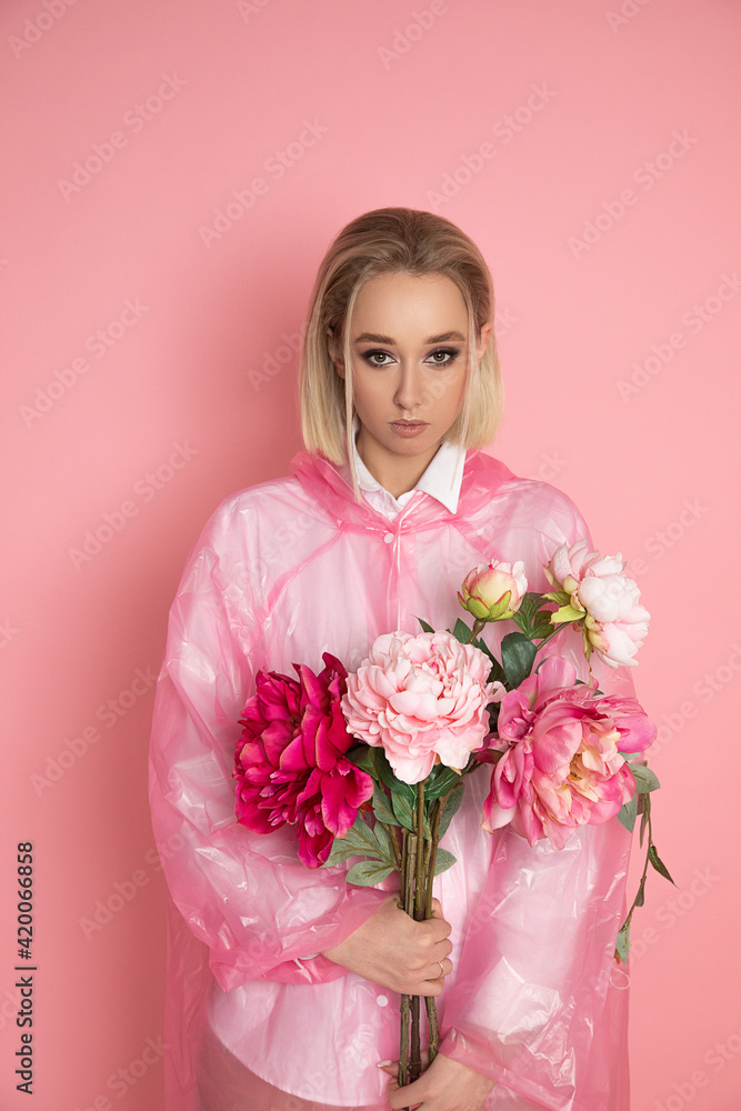 Photo of Beautiful woman with flowers peony in studio on pink background with blond hair Photo of Beautiful woman with flowers peony in studio on pink background with blond hair