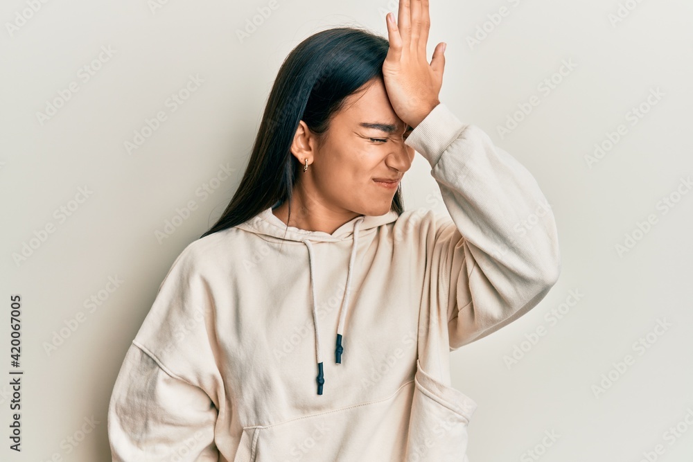 Young asian woman wearing casual sweatshirt surprised with hand on head for mistake, remember error. forgot, bad memory concept. Young asian woman wearing casual sweatshirt surprised with hand on head for mistake, remember error. forgot, bad memory concept.