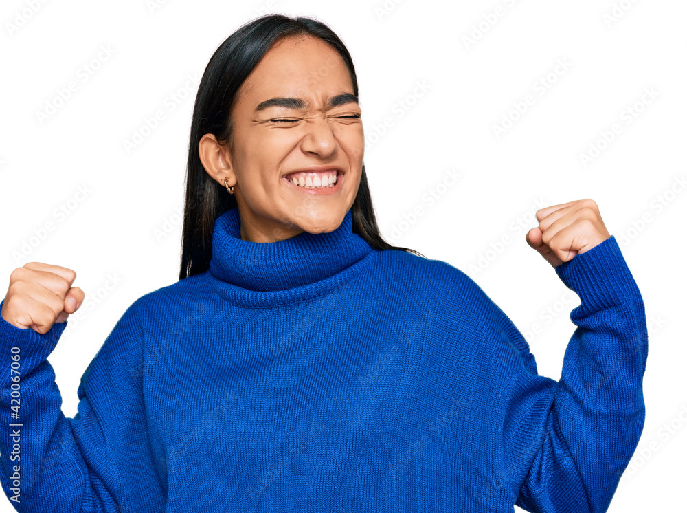 Young asian woman wearing casual winter sweater very happy and excited doing winner gesture with arms raised, smiling and screaming for success. celebration concept. Young asian woman wearing casual winter sweater very happy and excited doing winner gesture with arms raised, smiling and screaming for success. celebration concept.