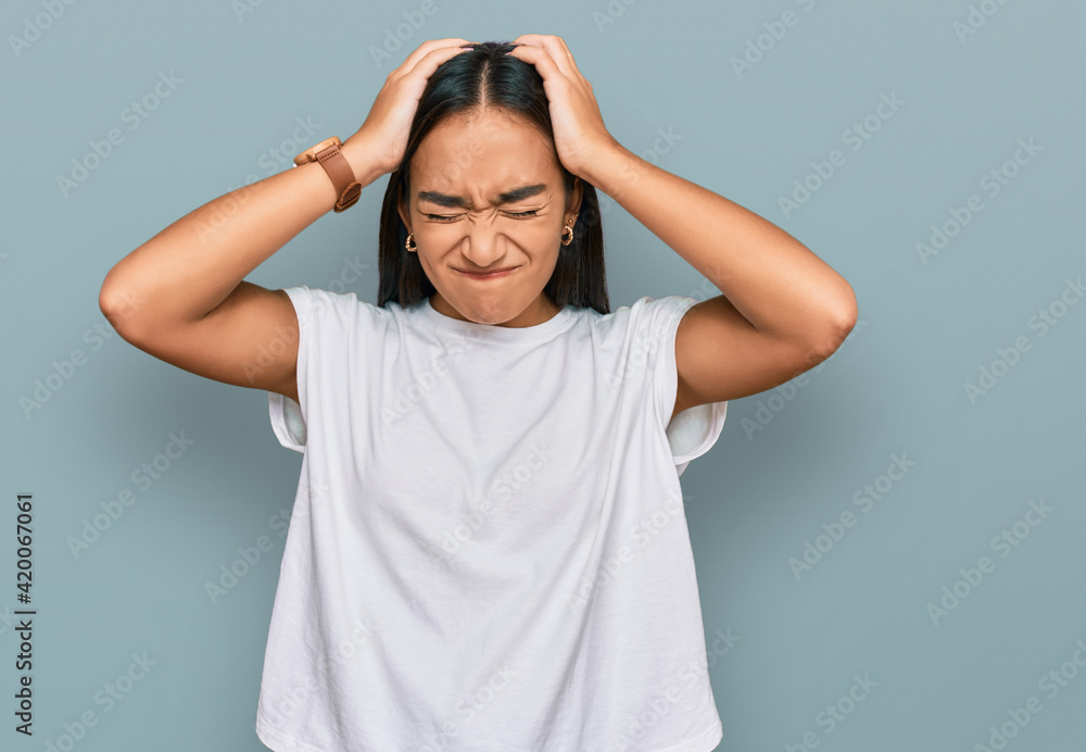 Young asian woman wearing casual white t shirt suffering from headache desperate and stressed because pain and migraine. hands on head. Young asian woman wearing casual white t shirt suffering from headache desperate and stressed because pain and migraine. hands on head.