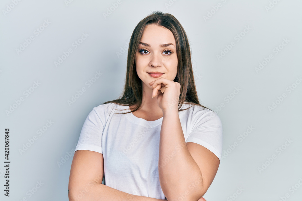 Young hispanic girl wearing casual white t shirt smiling looking confident at the camera with crossed arms and hand on chin. thinking positive. Young hispanic girl wearing casual white t shirt smiling looking confident at the camera with crossed arms and hand on chin. thinking positive.