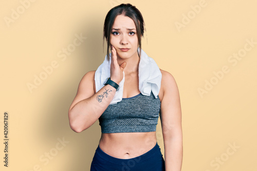 Young hispanic girl wearing sportswear and towel touching mouth with hand with painful expression because of toothache or dental illness on teeth. dentist