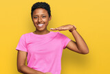 Young african american woman wearing casual clothes gesturing with hands showing big and large size sign, measure symbol. smiling looking at the camera. measuring concept.