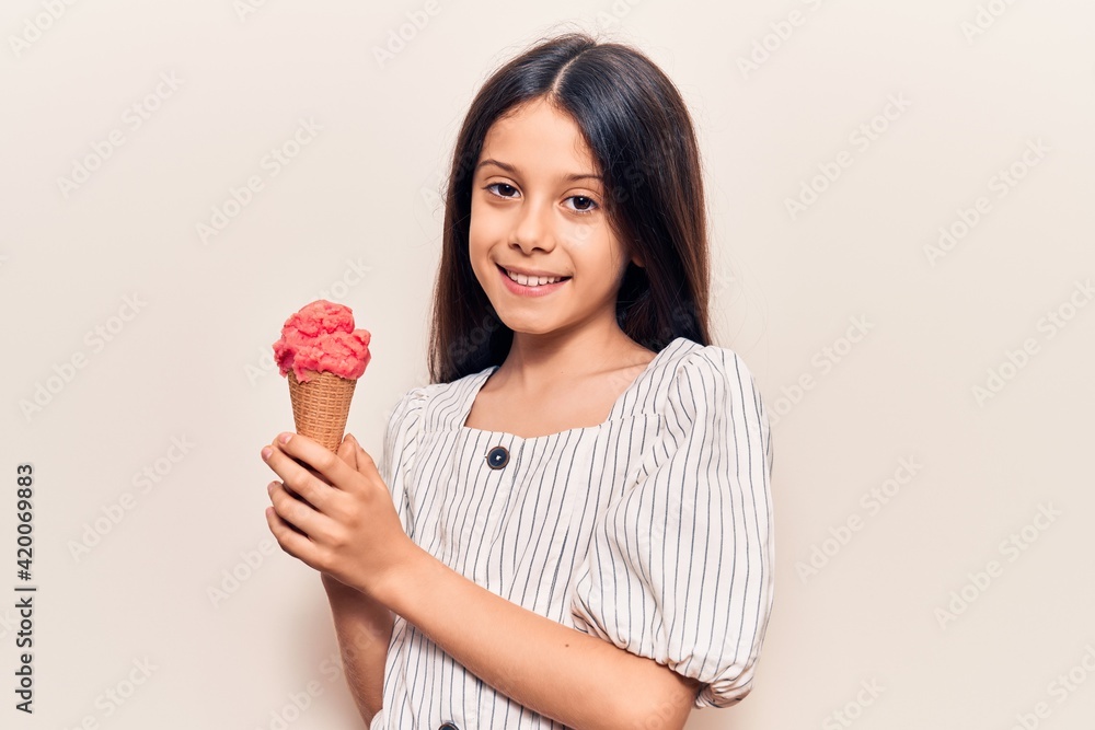 Beautiful child girl holding ice cream looking positive and happy standing and smiling with a confident smile showing teeth Beautiful child girl holding ice cream looking positive and happy standing and smiling with a confident smile showing teeth