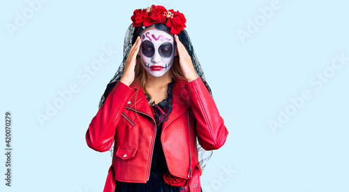 Woman wearing day of the dead costume over background with hand on head for pain in head because stress. suffering migraine.
