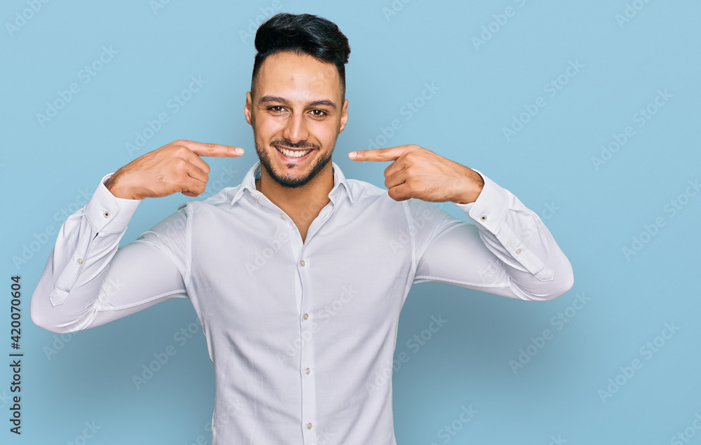 Young arab man wearing casual clothes smiling cheerful showing and pointing with fingers teeth and mouth. dental health concept. Young arab man wearing casual clothes smiling cheerful showing and pointing with fingers teeth and mouth. dental health concept.