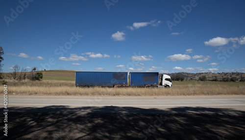 Truck on a freeway with plane flying overhead in Australian Country Town midway between Sydney and Melbourne with nice blue sky and lush green trees as a backdrop