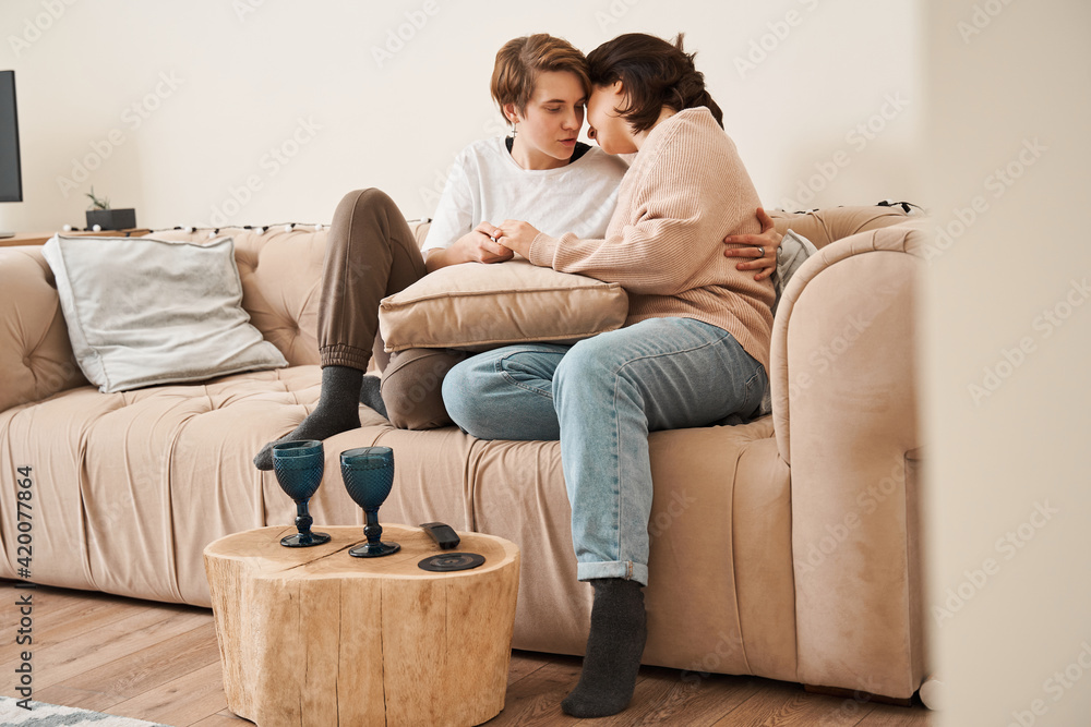 Couple in love enjoying their free time, while sitting on a couch Couple in love enjoying their free time, while sitting on a couch