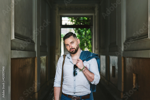 Handsome bearded man holding jacket over shoulder. Street fashion concept.