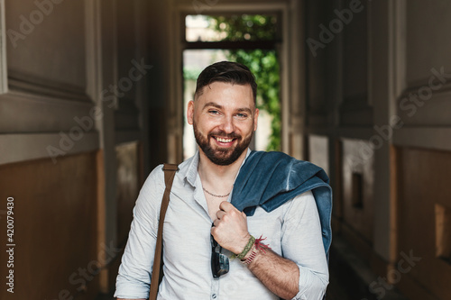 Portrait Of Young Handsome Man Smiling. Bearded businessman on the street.