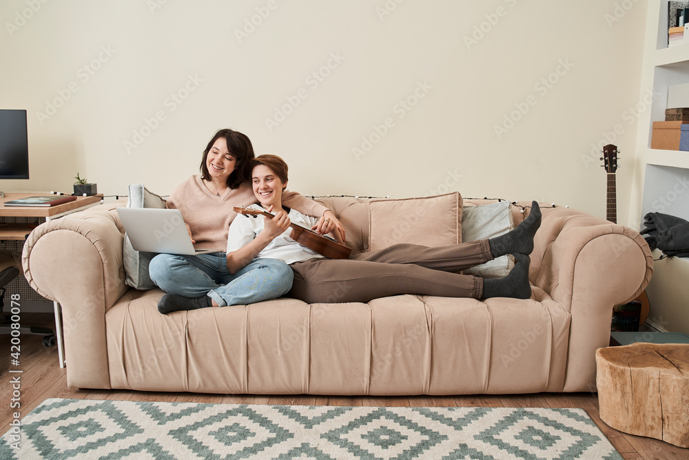 Girlfriend feeling relieved while learning how to at the ukulele with her woman Girlfriend feeling relieved while learning how to at the ukulele with her woman