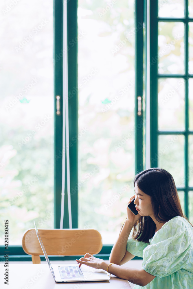 Happy casual beautiful woman talking smartphone and working on laptop in cafe Happy casual beautiful woman talking smartphone and working on laptop in cafe