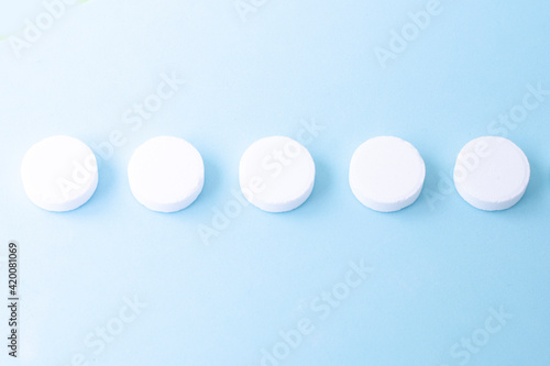 Round white medical pills on a blue background. Health concept