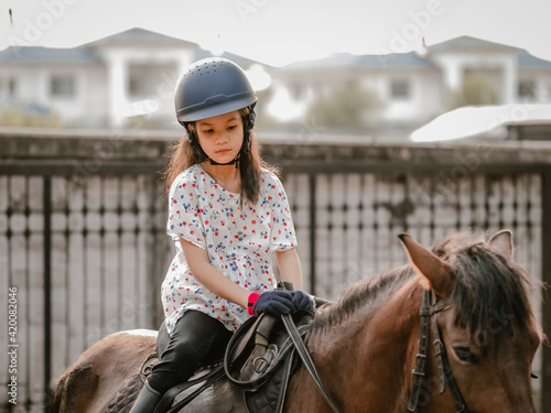 Asian shool kid girl with horse ,riding or practicing horse ridding at horse ranch © Paansaeng