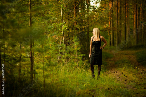 blonde girl in black dress in the woods, selective focus © Ekaterina
