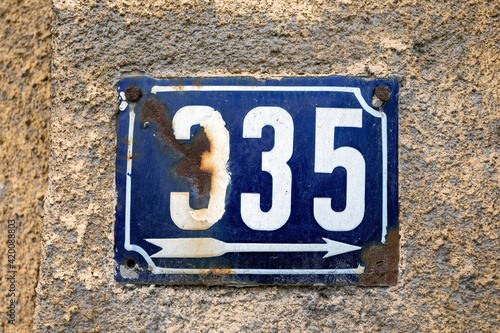 Number 335 number of houses apartments streets. White number of blue metal plate house number three hundred and thirty-five (335) on a rough wall