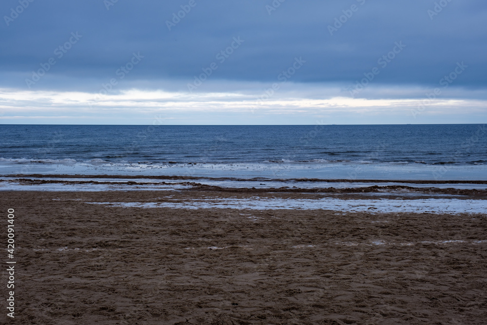icy winter beach near the sea with frozen sand and ice blocks in the water icy winter beach near the sea with frozen sand and ice blocks in the water