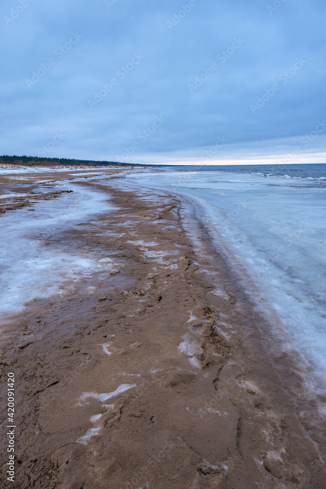 icy winter beach near the sea with frozen sand and ice blocks in the water icy winter beach near the sea with frozen sand and ice blocks in the water