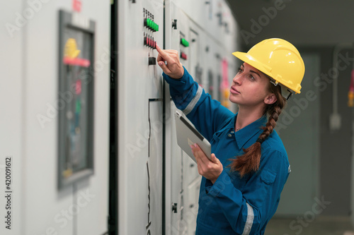 Portrait shot half body of young female electrical engineer in electrical control room, action thump up showing the good services working and professional concept.