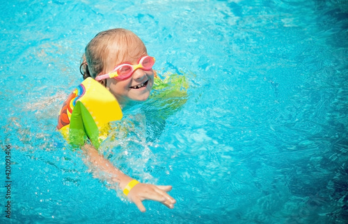 Happy young girl having fun in the water outdoors in the swimming pool