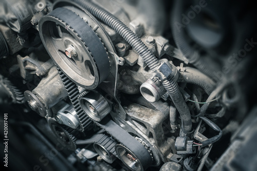 Replacement timing belt with rollers on the old diesel engine in a car service. Close up. Blur effect.