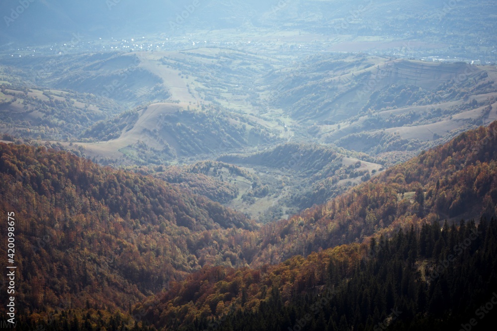 Mountain landscape. View from the top to a village in a valley. Photo in autumn golden colors with a haze.