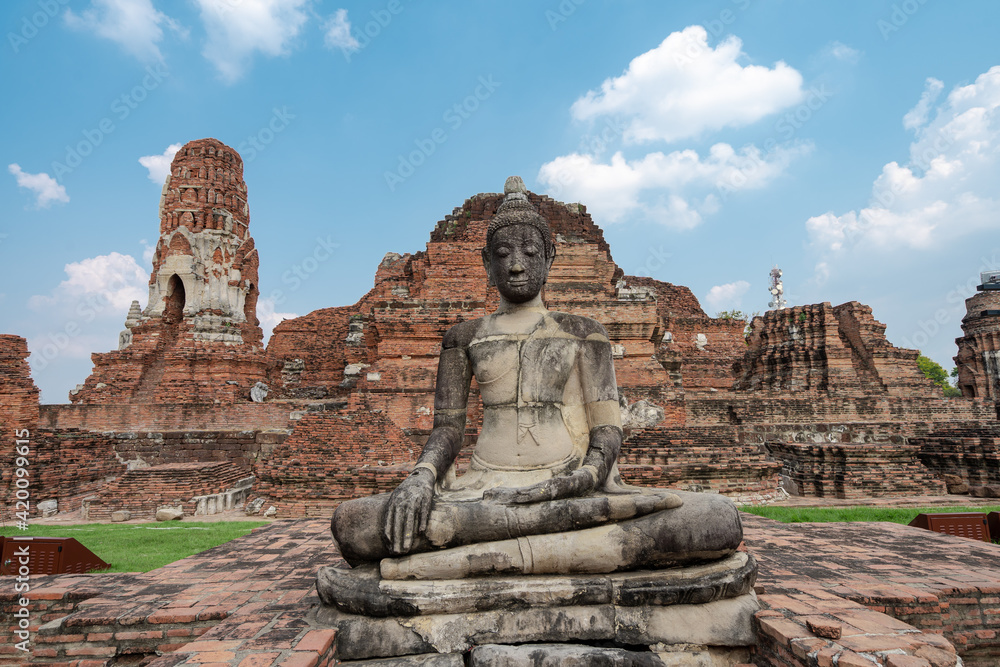 ancient meditated Buddha statue in front of old red-brick ruins architecture with clouds blue sky at Buddhist temple Wat Phra Mahathat at Ayutthaya, Thailand, travel place, religion landmark