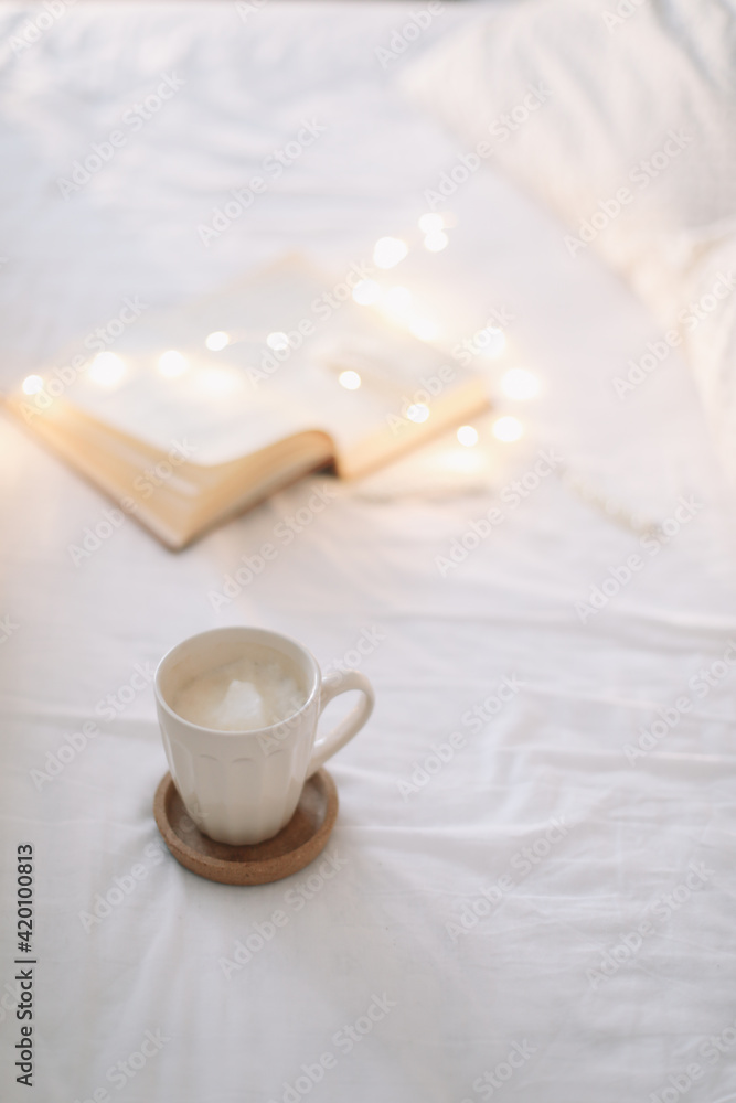 Reading and having breakfast in bed. Coffee cup and a book in bed. Cozy sunny morning at home. Reading and having breakfast in bed. Coffee cup and a book in bed. Cozy sunny morning at home.
