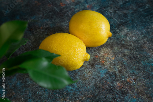 Two lemons on a dark rusty metal background. Cold medicine. Fruit for lemonade.