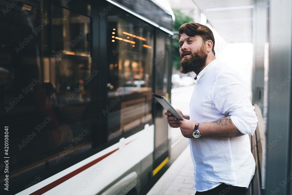 Attentive male employee using tablet on bus stop Attentive male employee using tablet on bus stop