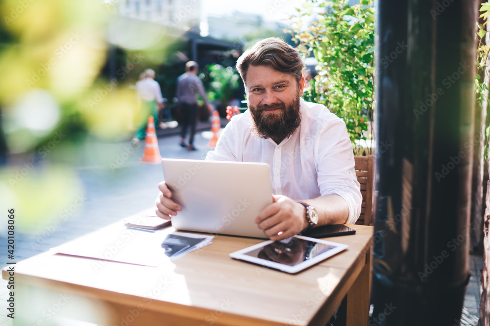 Positive businessman using laptop while working remotely Positive businessman using laptop while working remotely