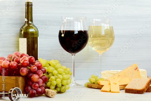 glasses with wine, wine bottle, different kinds of cheese, grapes 