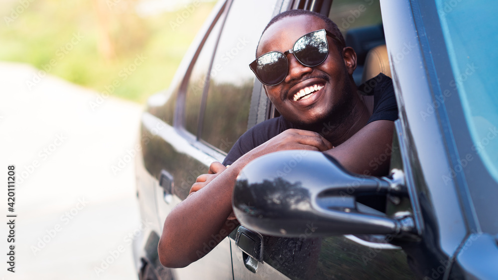 African man driver wearing sunglasses and smiling while sitting in a car.16:9 style