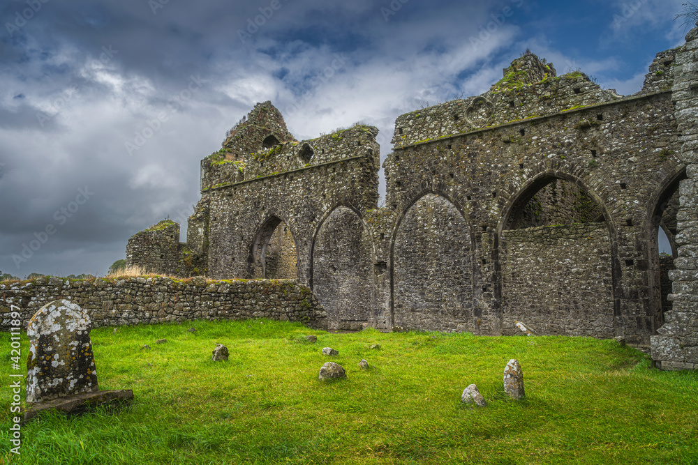 Tombstones and ruins of old abandoned Hore Abbey with dramatic storm sky. Located next to Rock of Cashel castle, County Tipperary, Ireland