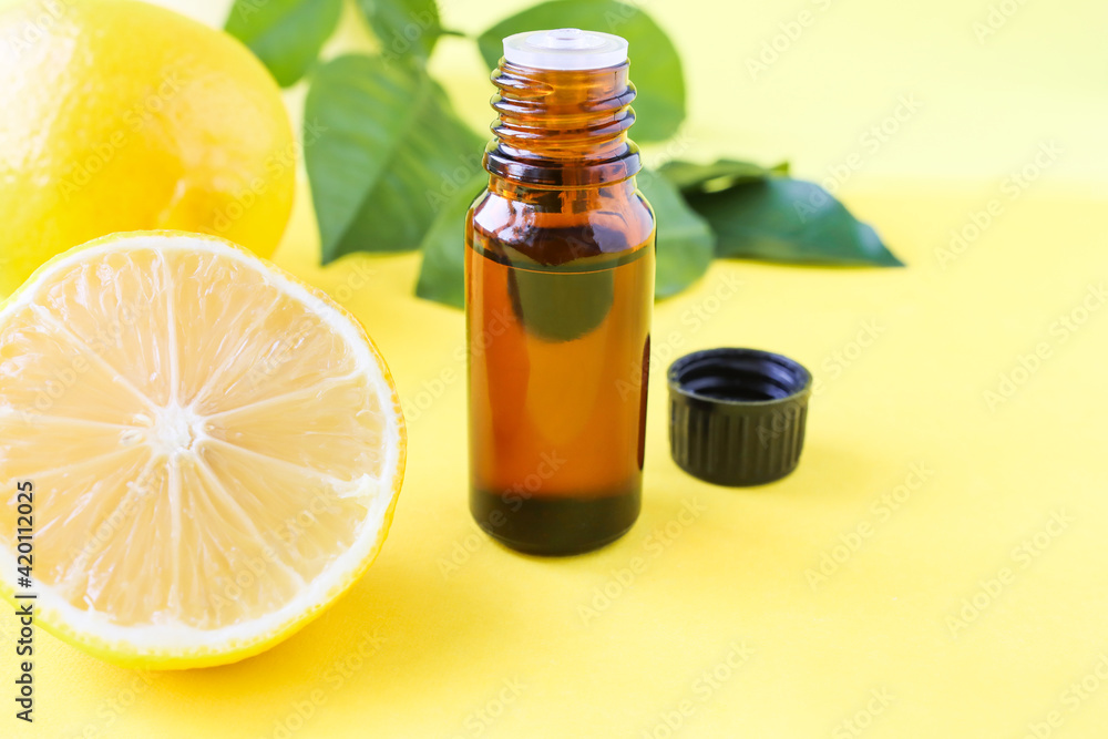 Aromatherapy oil for massage and treatments. Lemon oil in a bottle with an open lid on a yellow background. Aromatherapy oil for massage and treatments. Lemon oil in a bottle with an open lid on a yellow background.