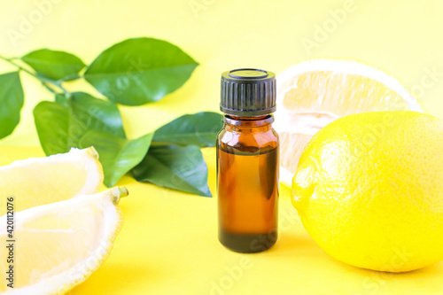Fototapeta Naklejka Na Ścianę i Meble -  Lemon oil on a bright background and yellow citrus fruits. Aromatherapy, aroma. The use of oil in medicine.