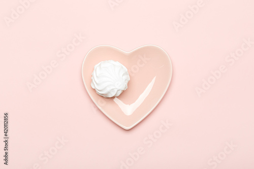 White marshmallow on a pink plate in the shape of a heart on a pink background
