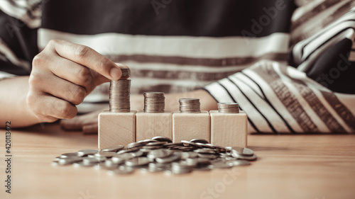 Woman's hands put the coins arranged in steps, Managing your finances or saving money for future use, Saving for investment, Saving money for business growth or long-term profitability.