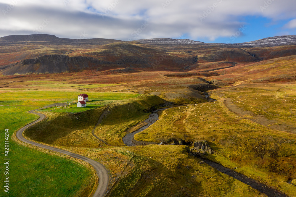 Sheep farm in Iceland from up high. combination farm and landscape shot with background hills, waterfall, and river during autumn