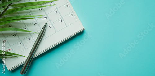 Картината върху платно close up top view on white calendar 2020 with pen and tropical leaves on blue ta