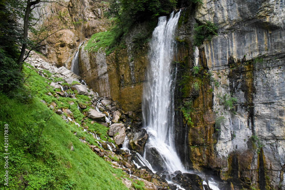 Beautiful waterfall in switzerland rushing down a cliff and bursting onto a steep rocky mountainside