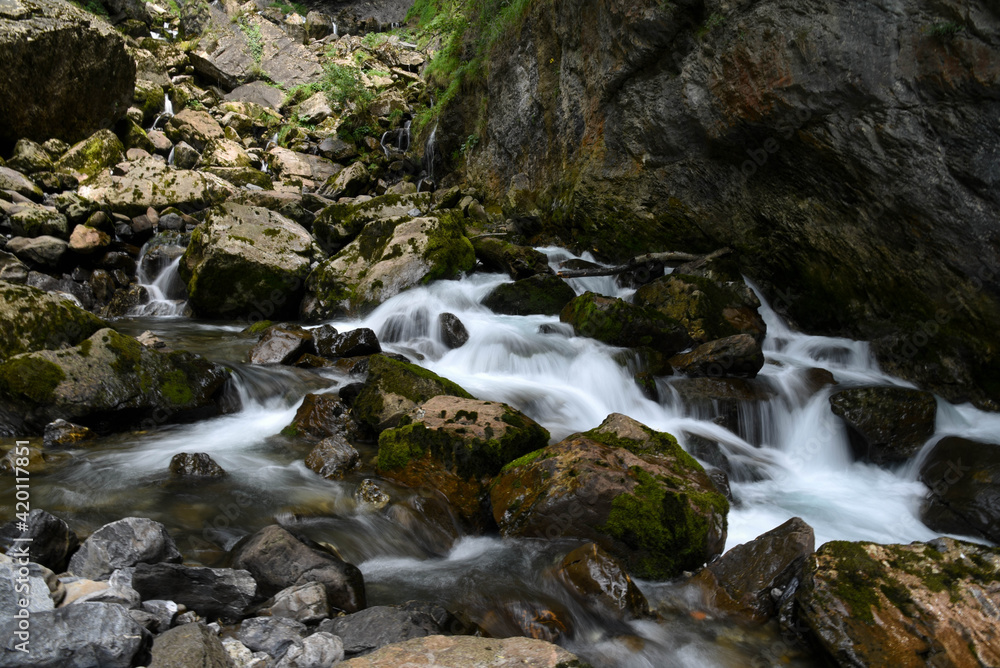 Beautiful photo of rapids and small waterfalls between big moss covered rocks. Beautiful photo of rapids and small waterfalls between big moss covered rocks.