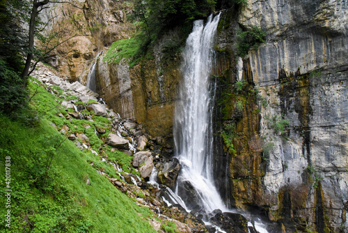 Beautiful waterfall in switzerland rushing down a cliff and bursting onto a steep rocky mountainside © Jannis