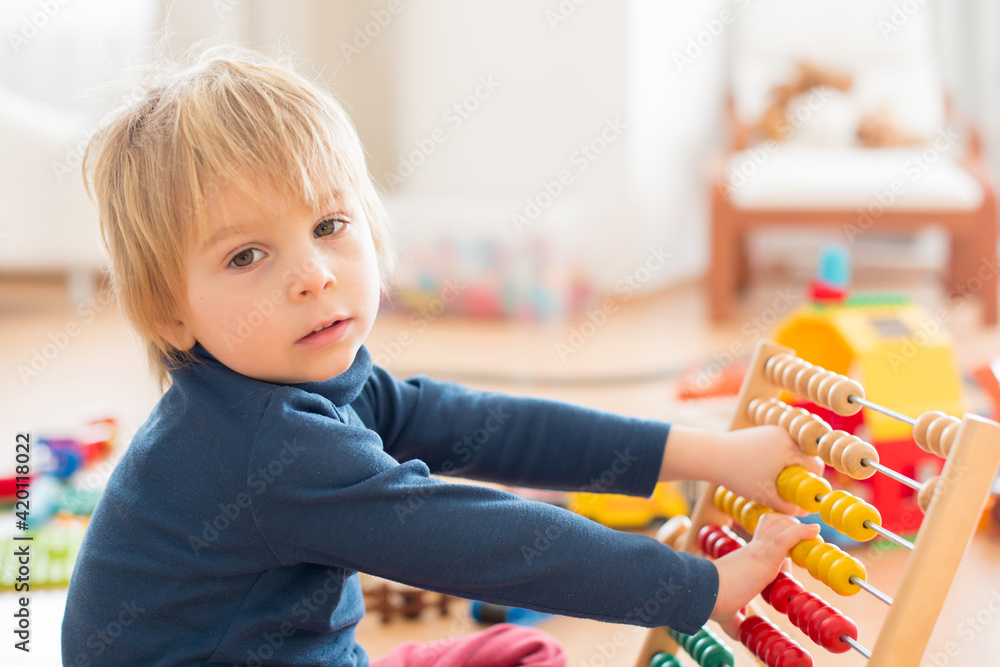 Sweet blond preschool child, toddler boy, playing with abacus at home,construction on the floor behing Sweet blond preschool child, toddler boy, playing with abacus at home,construction on the floor behing
