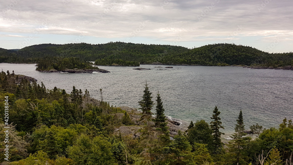 Scenic untouched landscape in the Pukaskwa Nationalpark. Mixed woodland surrounding a calm bay with waves washing around two wooded islands.